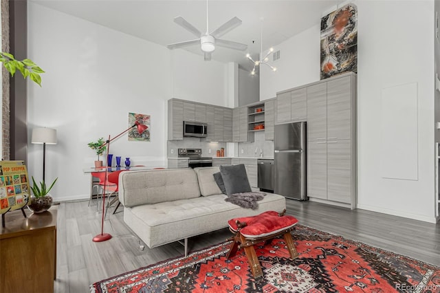 living room featuring visible vents, baseboards, a towering ceiling, and dark wood finished floors