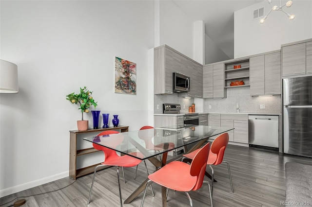 dining room with visible vents, baseboards, a towering ceiling, and dark wood-style flooring