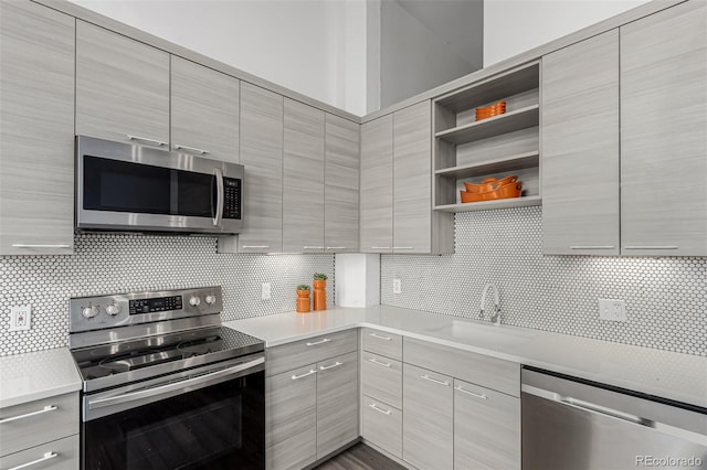 kitchen with a sink, open shelves, stainless steel appliances, and modern cabinets