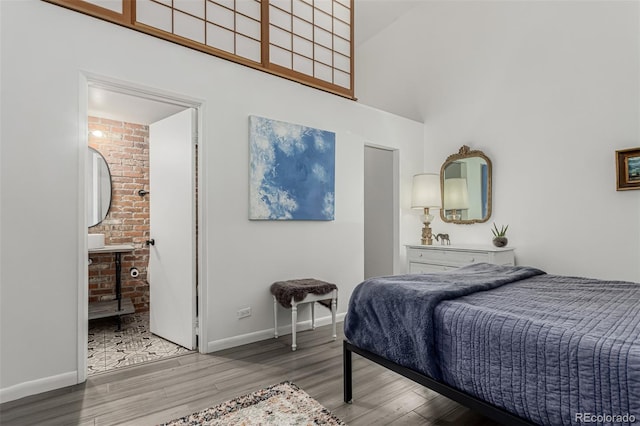 bedroom with a high ceiling, baseboards, and wood finished floors