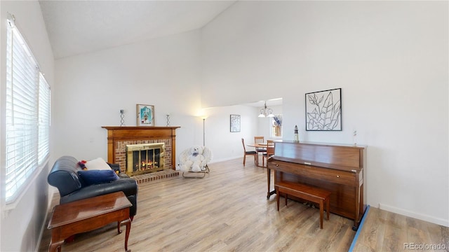 sitting room featuring a fireplace, high vaulted ceiling, and light hardwood / wood-style flooring