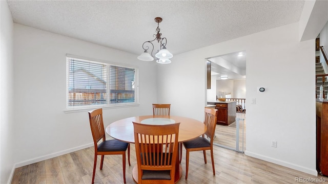 dining room with a chandelier, a textured ceiling, and light hardwood / wood-style flooring