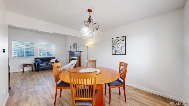 dining area featuring a chandelier, light hardwood / wood-style flooring, and a brick fireplace