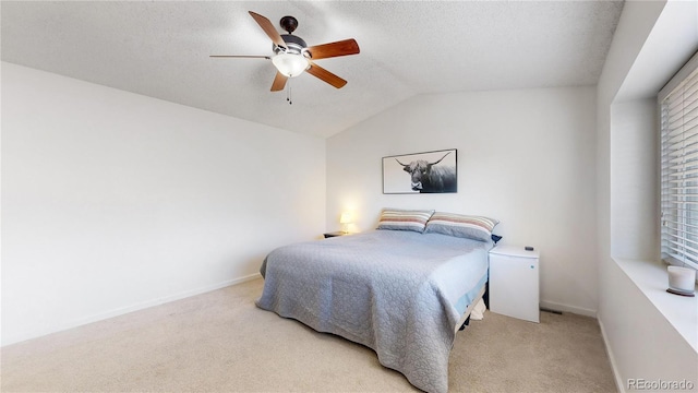 carpeted bedroom with a textured ceiling, ceiling fan, and vaulted ceiling