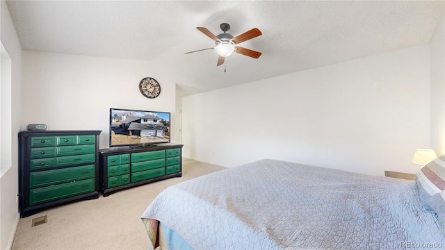 bedroom with ceiling fan, light carpet, and a textured ceiling