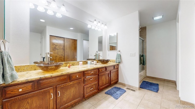 bathroom featuring tile patterned flooring, vanity, and combined bath / shower with glass door