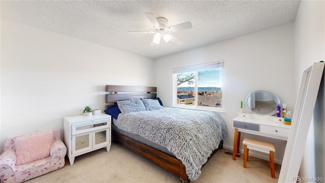 bedroom featuring ceiling fan, light colored carpet, and a textured ceiling