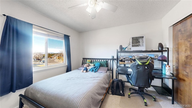 carpeted bedroom with ceiling fan and a textured ceiling