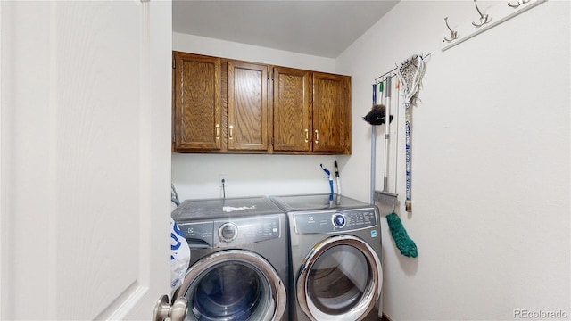 laundry room featuring washer and clothes dryer and cabinets