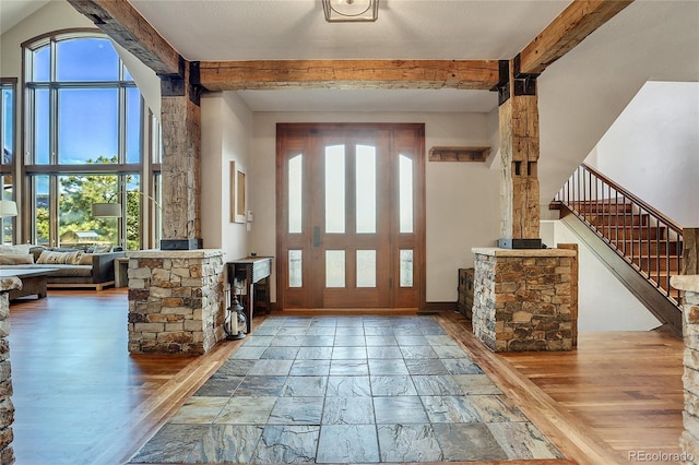 foyer entrance with beam ceiling, a wealth of natural light, and hardwood / wood-style floors