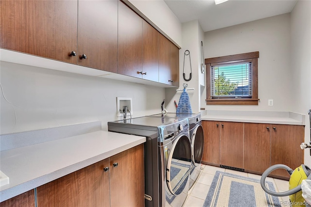 laundry room with light tile patterned flooring, cabinets, and washing machine and dryer