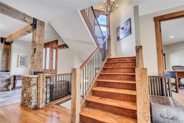 stairway with hardwood / wood-style floors and an inviting chandelier