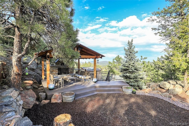 exterior space with an outdoor stone fireplace and a wooden deck