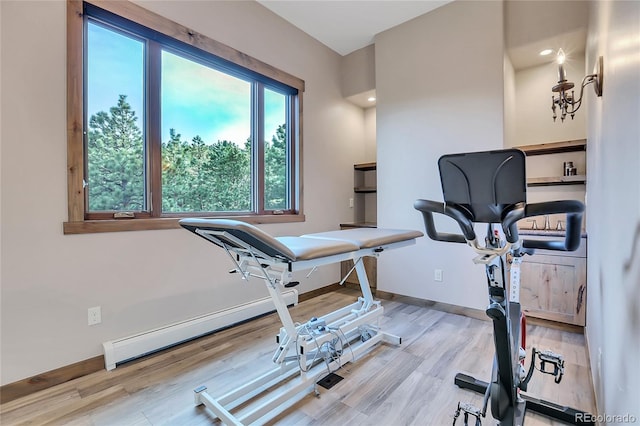 workout area with wood-type flooring and a baseboard heating unit