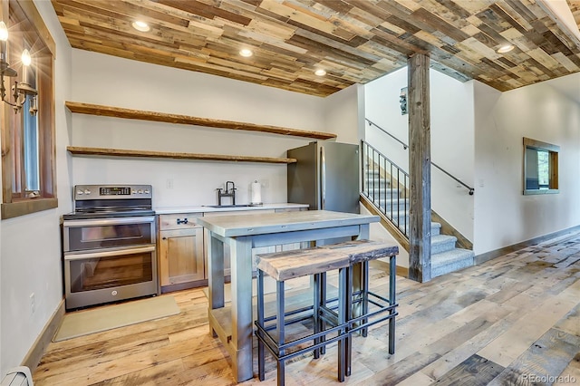 kitchen with light wood-type flooring, stainless steel appliances, and baseboard heating