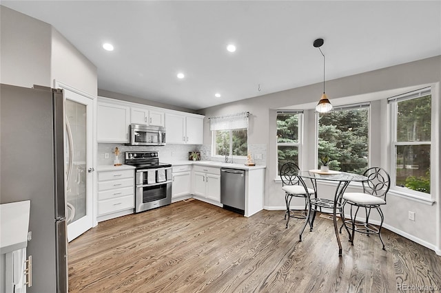 10571 Garfield St, Thornton, CO 80233 - kitchen featuring appliances with stainless steel finishes, light wood-style floors, tasteful backsplash, white cabinetry, and light countertops