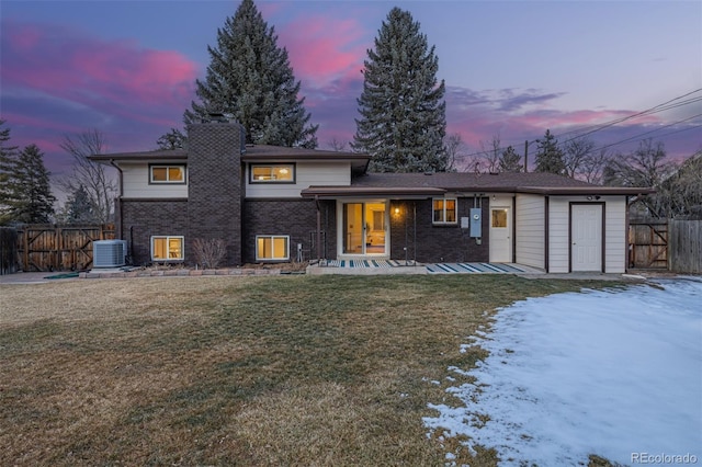 view of front of property featuring central AC unit and a lawn