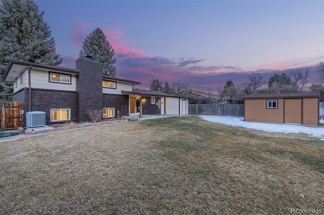 back house at dusk featuring a storage shed, a yard, and central air condition unit