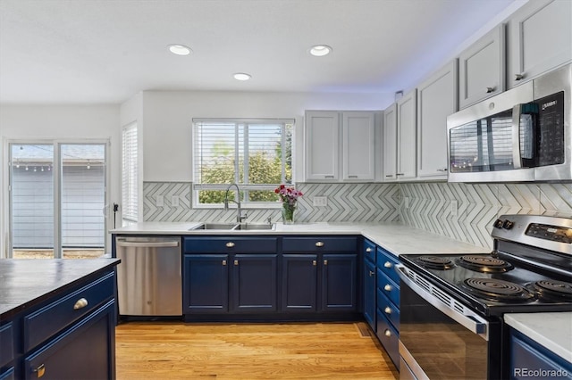 10517 Madison St, Thornton, CO 80233 - kitchen with stainless steel appliances, a sink, blue cabinetry, plenty of natural light, and recessed lighting