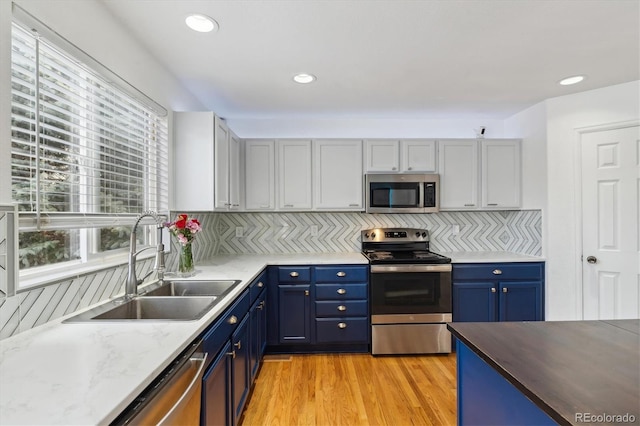 10517 Madison St, Thornton, CO 80233 - kitchen featuring appliances with stainless steel finishes, a sink, blue cabinetry, healthy amount of natural light, and recessed lighting