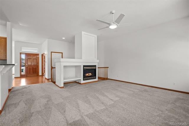 14447 Inca Ct, Westminster, CO 80023 - unfurnished living room with light colored carpet, ceiling fan, a glass covered fireplace, and baseboards