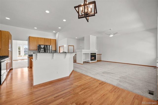 14447 Inca Ct, Westminster, CO 80023 - kitchen with fridge with ice dispenser, a kitchen breakfast bar, a fireplace, brown cabinetry, and light wood-type flooring