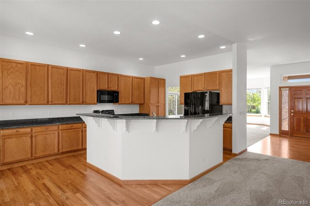 14447 Inca Ct, Westminster, CO 80023 - kitchen featuring black appliances, a breakfast bar, recessed lighting, light wood-style flooring, and brown cabinets