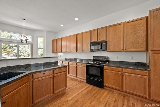 14447 Inca Ct, Westminster, CO 80023 - kitchen with black appliances, light wood finished floors, recessed lighting, hanging light fixtures, and brown cabinetry