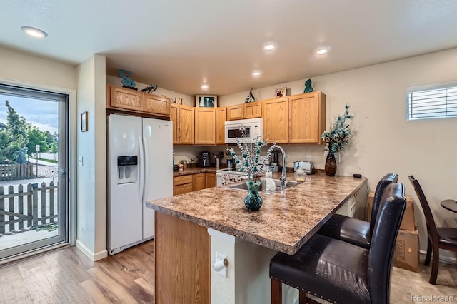 1199 Hummingbird Cir, Longmont, CO 80501 - kitchen featuring white appliances, a peninsula, a breakfast bar, light wood-style floors, and recessed lighting