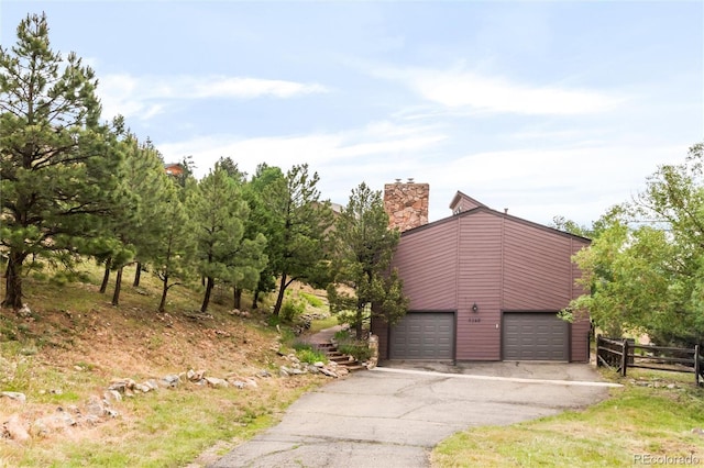3260 Bit Rd, Evergreen, CO 80439 - view of property exterior featuring driveway, a garage, and a chimney