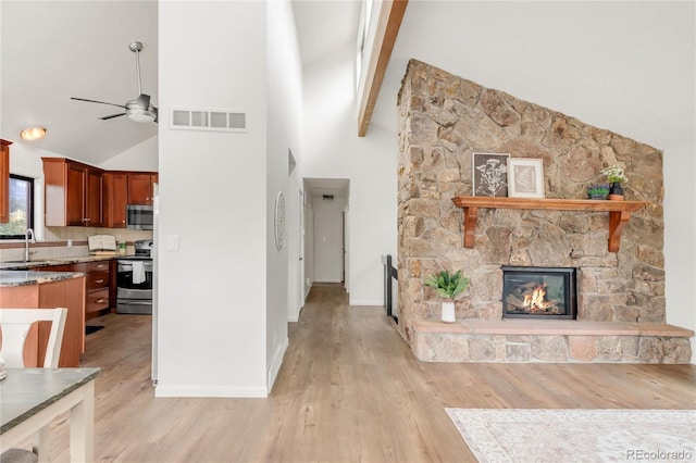 3260 Bit Rd, Evergreen, CO 80439 - unfurnished living room featuring ceiling fan, light wood-style flooring, a fireplace, high vaulted ceiling, and beam ceiling