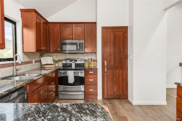 3260 Bit Rd, Evergreen, CO 80439 - kitchen with appliances with stainless steel finishes, tasteful backsplash, dark stone countertops, light wood-style flooring, and vaulted ceiling