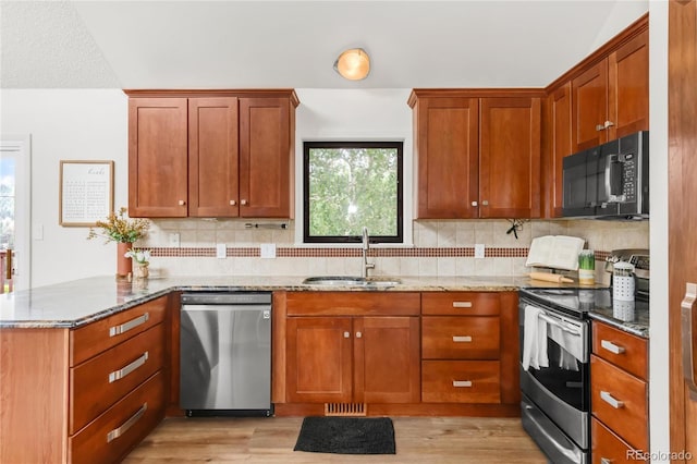 3260 Bit Rd, Evergreen, CO 80439 - kitchen with appliances with stainless steel finishes, light stone counters, a peninsula, tasteful backsplash, and light wood finished floors