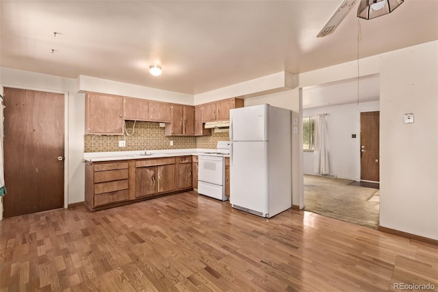 3182 W Radcliff Dr, Englewood, CO 80110 - kitchen with white appliances, under cabinet range hood, light countertops, a sink, and light wood finished floors