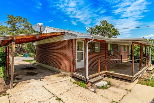 3182 W Radcliff Dr, Englewood, CO 80110 - view of property exterior featuring concrete driveway, brick siding, a carport, and a wooden deck