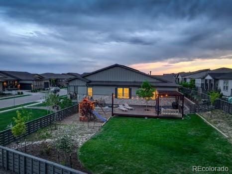7029 Sagerock St, Castle Pines, CO 80108 - back of house at dusk featuring a fenced backyard and a deck