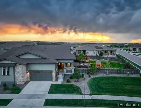 7029 Sagerock St, Castle Pines, CO 80108 - view of front of house with driveway, a garage, stone siding, and a front lawn