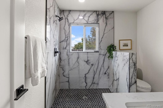 bathroom with a tile shower and toilet