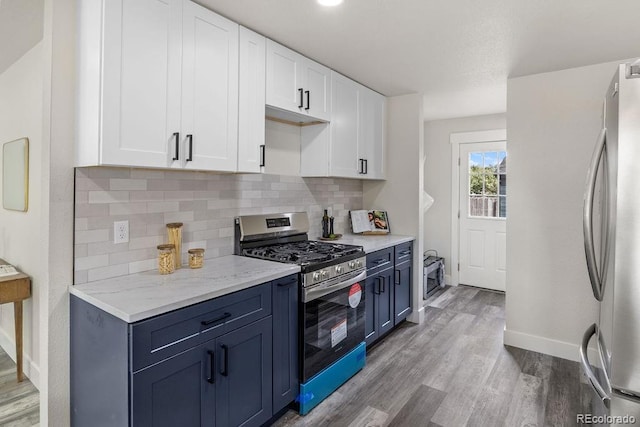 kitchen with blue cabinets, appliances with stainless steel finishes, light wood-type flooring, and white cabinets