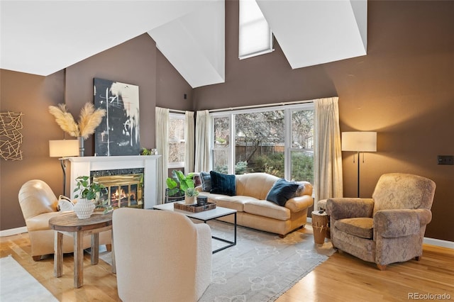 living room featuring a towering ceiling, a high end fireplace, and light hardwood / wood-style flooring