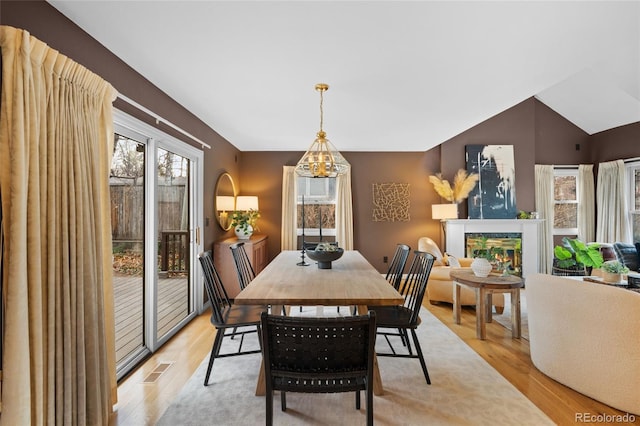 dining area featuring light hardwood / wood-style floors, an inviting chandelier, and vaulted ceiling