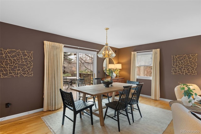 dining space with light wood-type flooring, an inviting chandelier, and a wealth of natural light