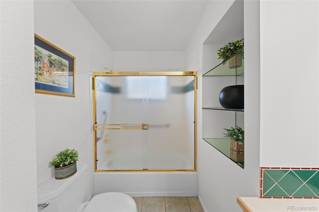 bathroom featuring shower / bath combination with glass door, tile patterned floors, and toilet