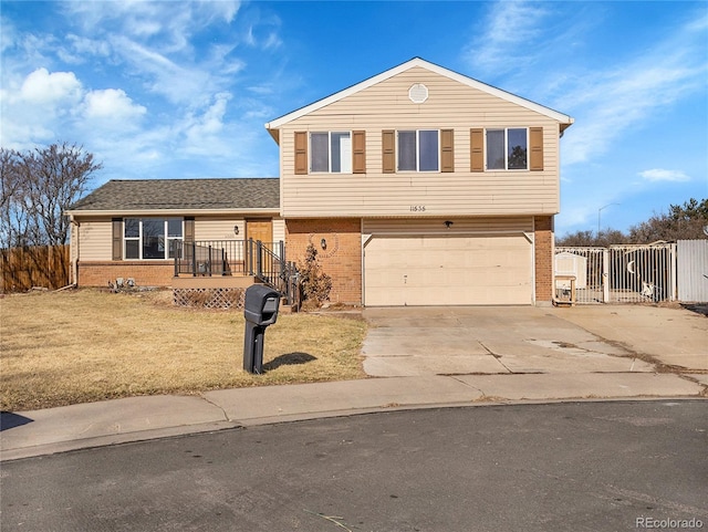 view of front of house featuring a front lawn, brick siding, driveway, and a gate