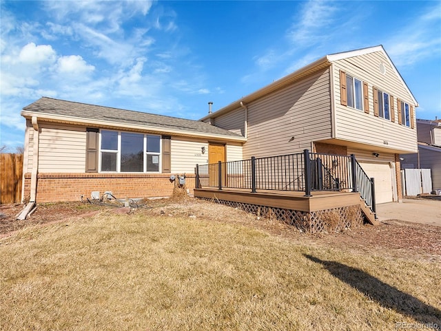 back of house featuring brick siding, a garage, a yard, a deck, and driveway