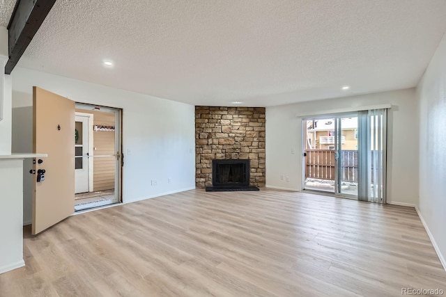 unfurnished living room with a textured ceiling, light wood-type flooring, and a fireplace