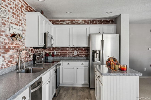 kitchen with sink, white cabinets, brick wall, and appliances with stainless steel finishes