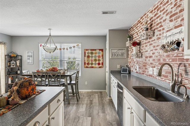 kitchen with sink, white cabinets, a textured ceiling, and light hardwood / wood-style flooring