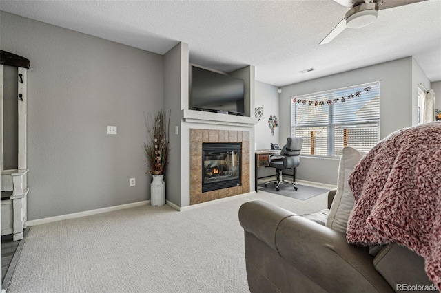 living room with ceiling fan, light colored carpet, a fireplace, and a textured ceiling