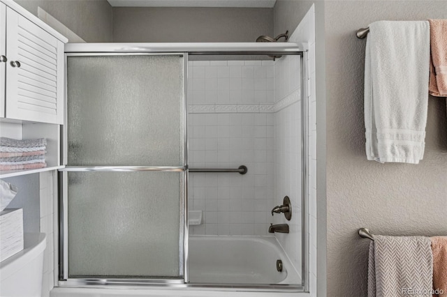 bathroom with combined bath / shower with glass door and toilet